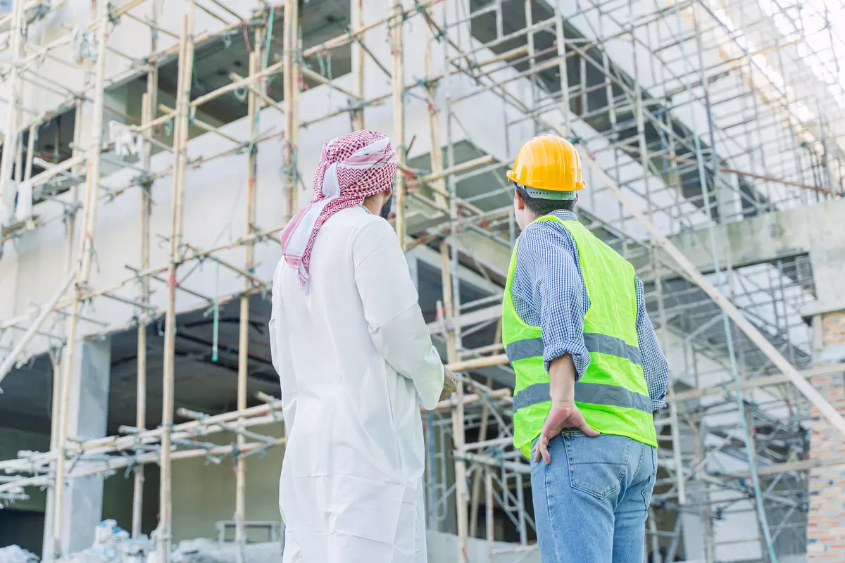 مهندس ومشرف موقع أمام واجهة مبنى مغطاة بالسقالات